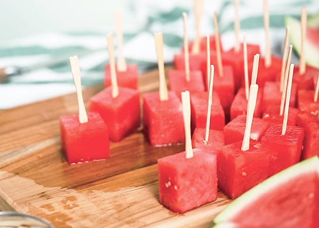 watermelon cubes on a wooden cutting board with popsicle sticks in them