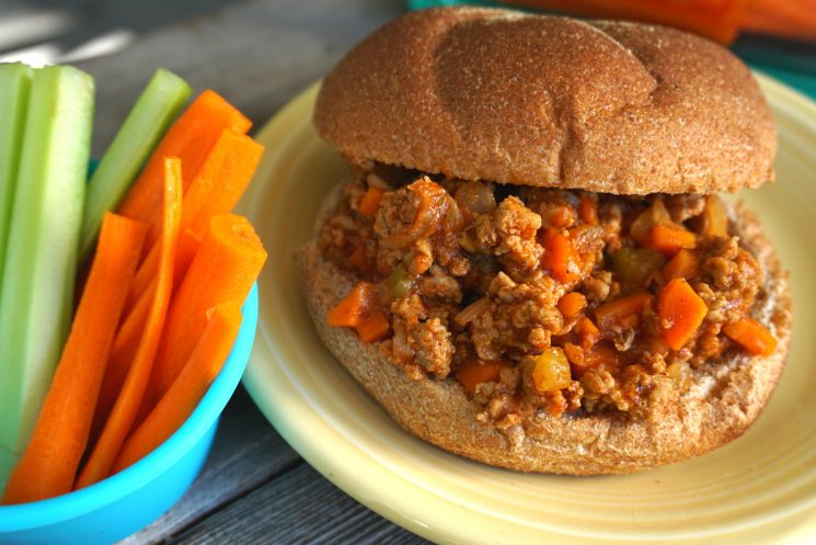 sloppy joes on a whole wheat bun served with carrot and celery sticks