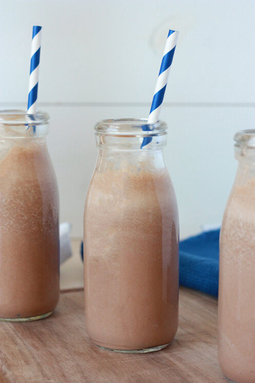 close up view of a milk bottle with chocolate milk and blue and white striped straw