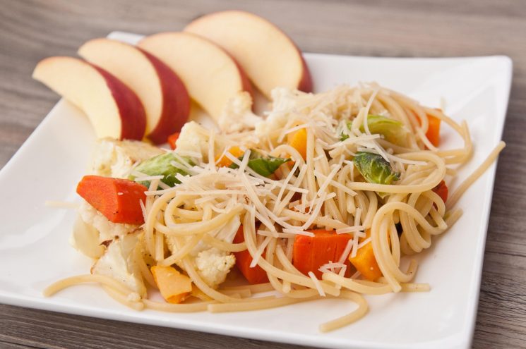 spaghetti with vegetables and cheese on a white plate