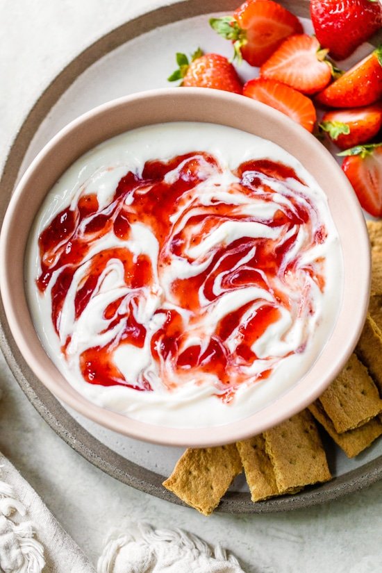 Cheesecake Dip with strawberry preserves swirled on top.