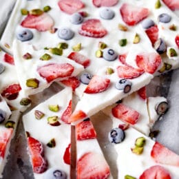 frozen yogurt bark broken into pieces with strawberries, blueberries, and pistachios