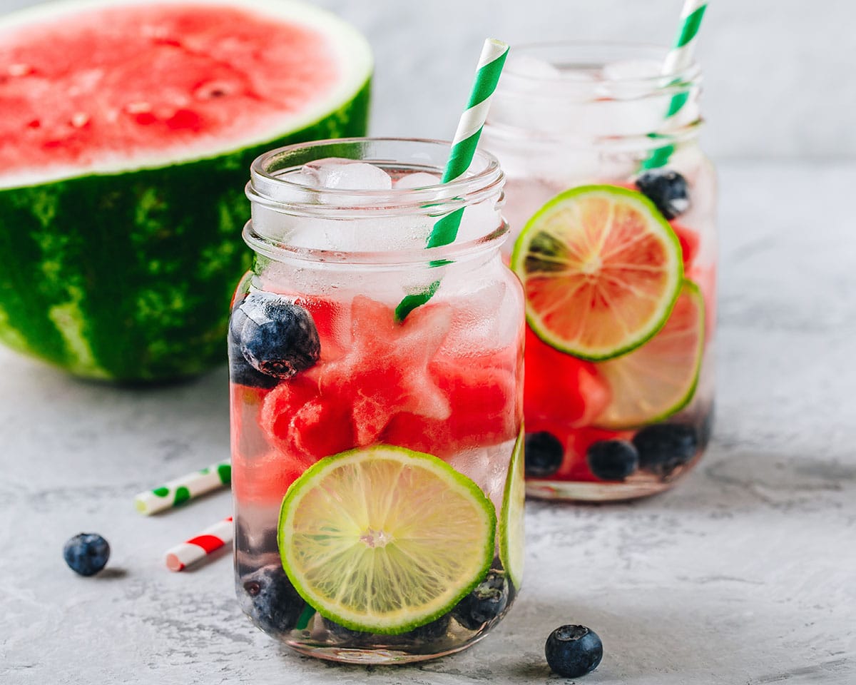 Infused fruit water with watermelon, lime and blueberry. Ice cold summer drink in glass mason jar