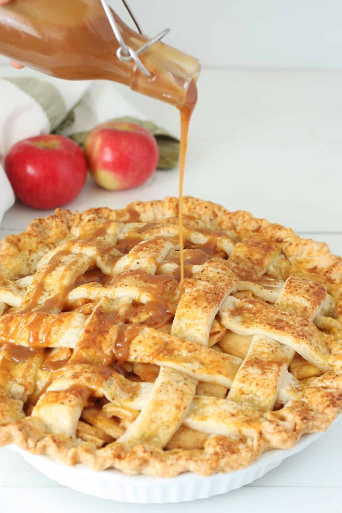 An apple pie being drizzled with homemade caramel sauce