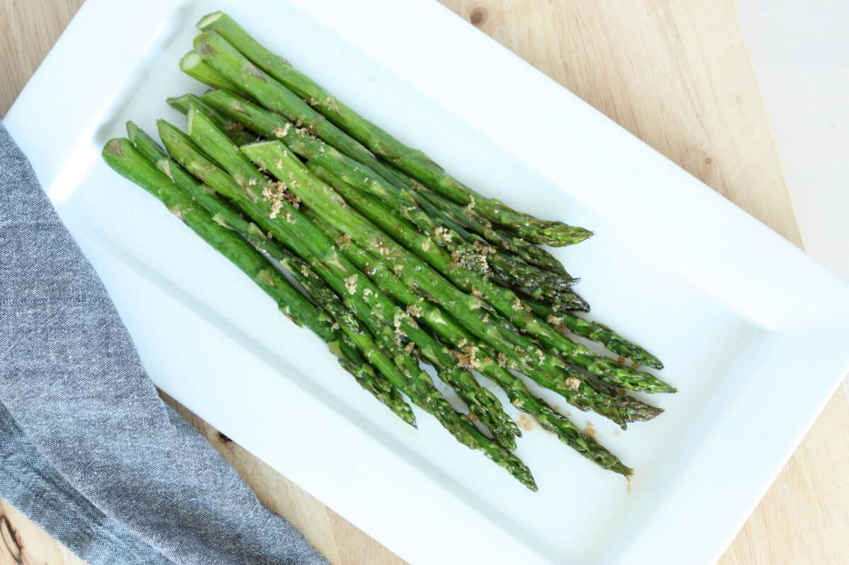 oven roasted asparagus on a white plate with a blue dish towel