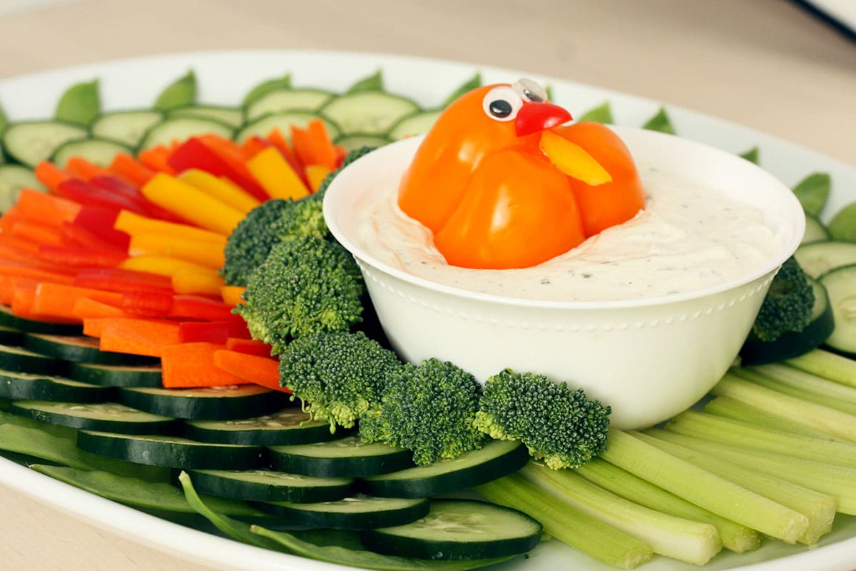cucumber, carrot, and pepper slices arranged to look like turkey feathers with a bowl of ranch dip
