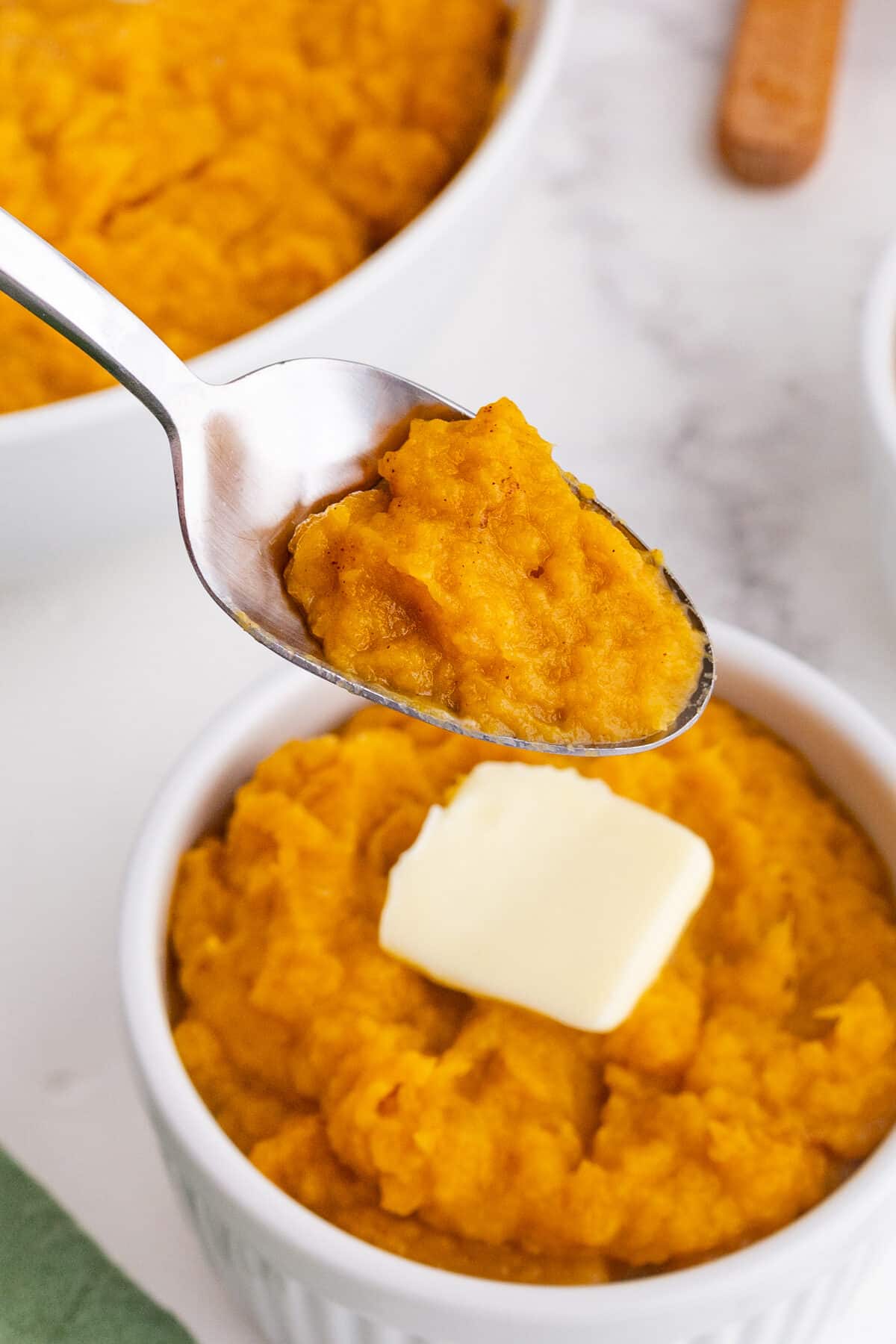 a spoonful of mashed sweet potatoes being lifted out of a bowl