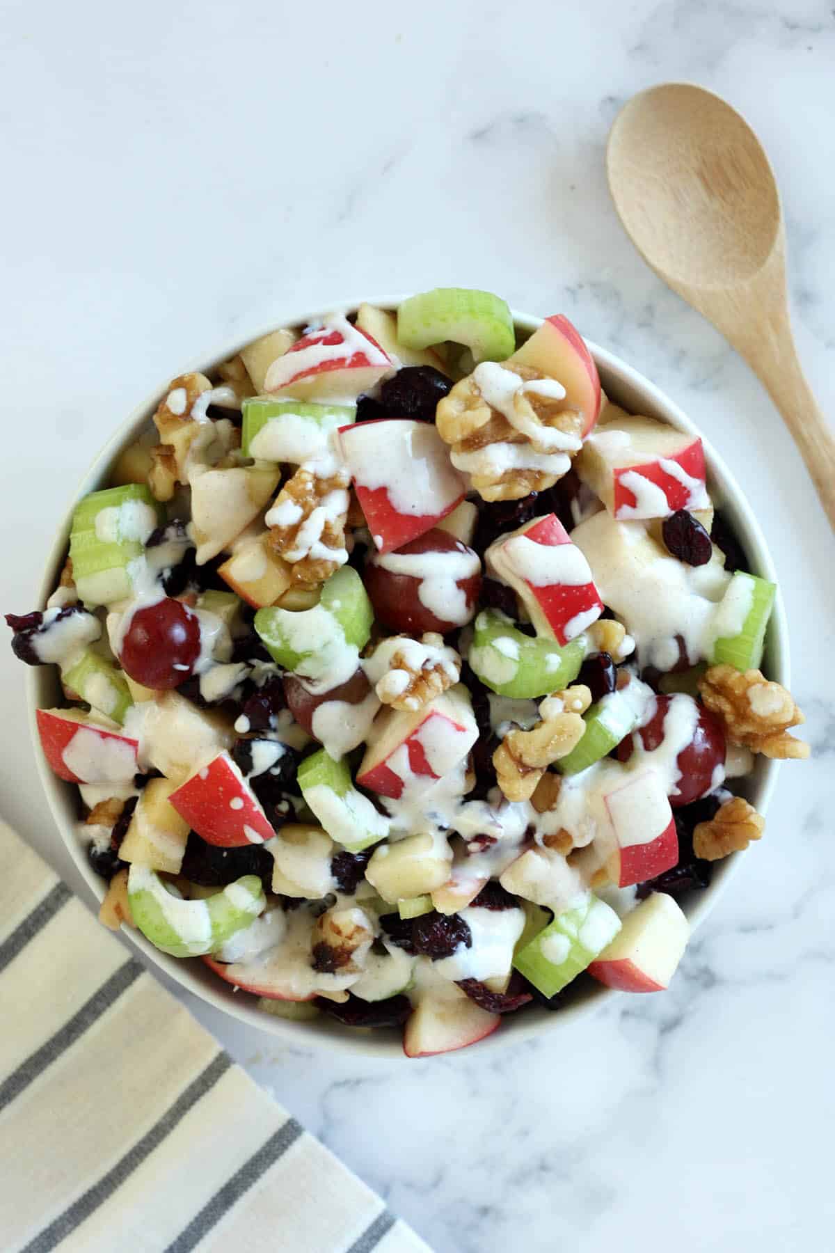 waldorf salad recipe in a bowl with a wooden spoon