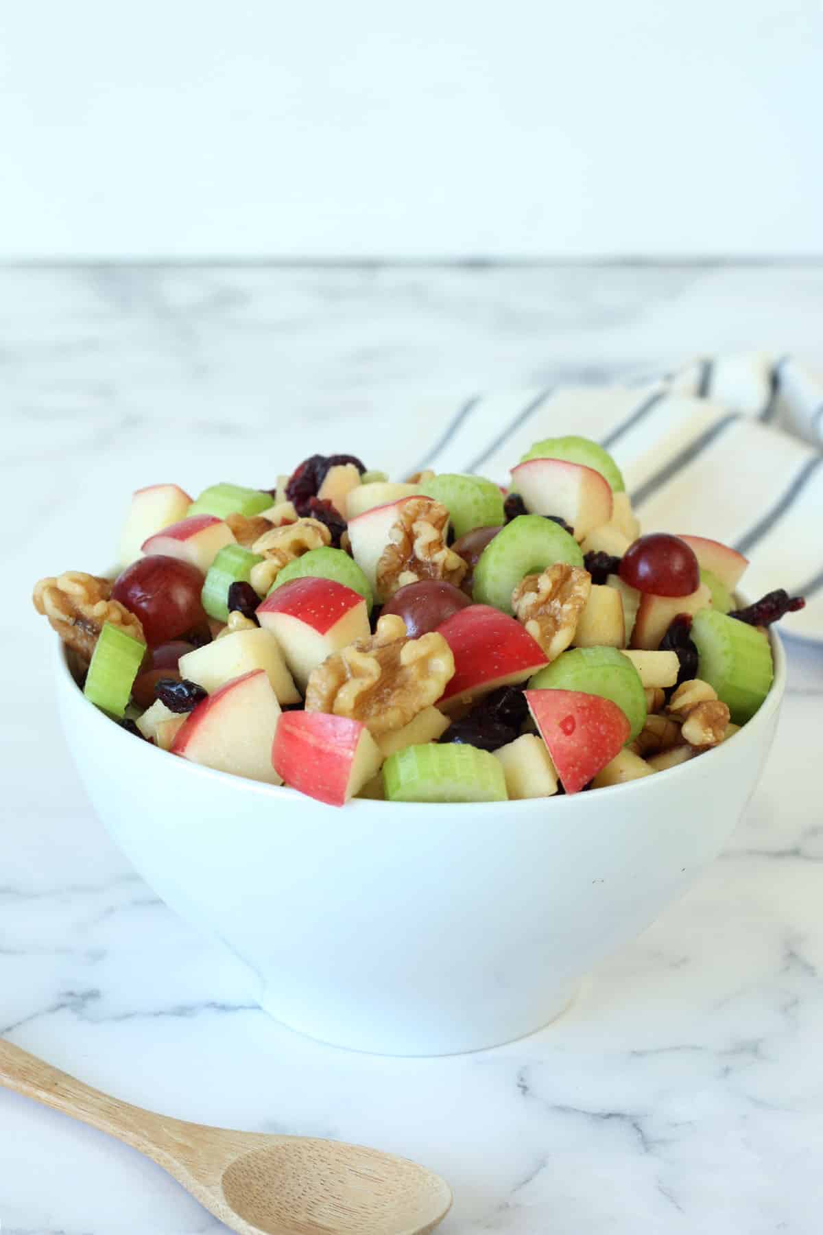 apples, celery, grapes and walnuts in a white bowl