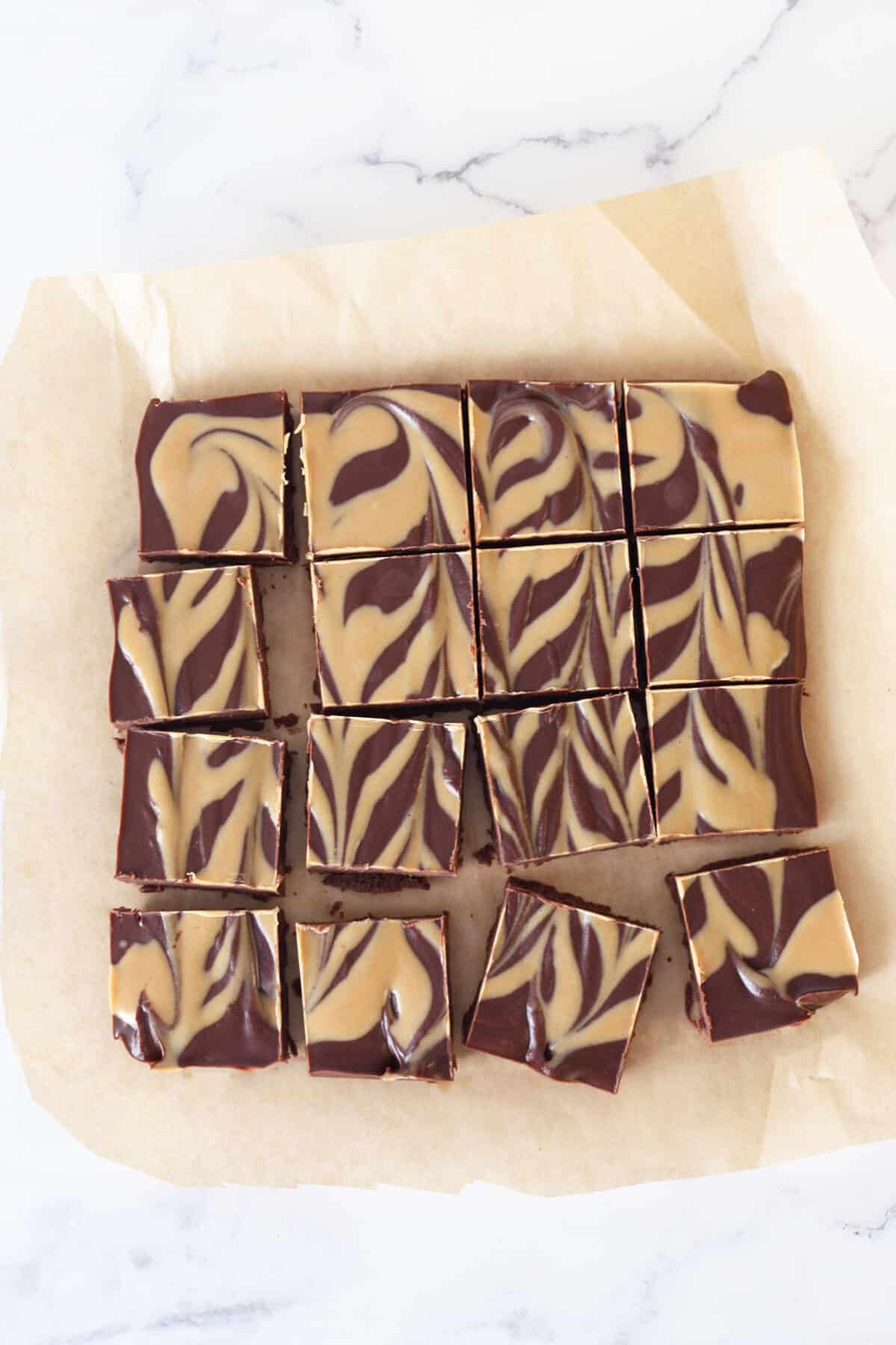 chocolate peanut butter fudge squares on a sheet of parchment paper