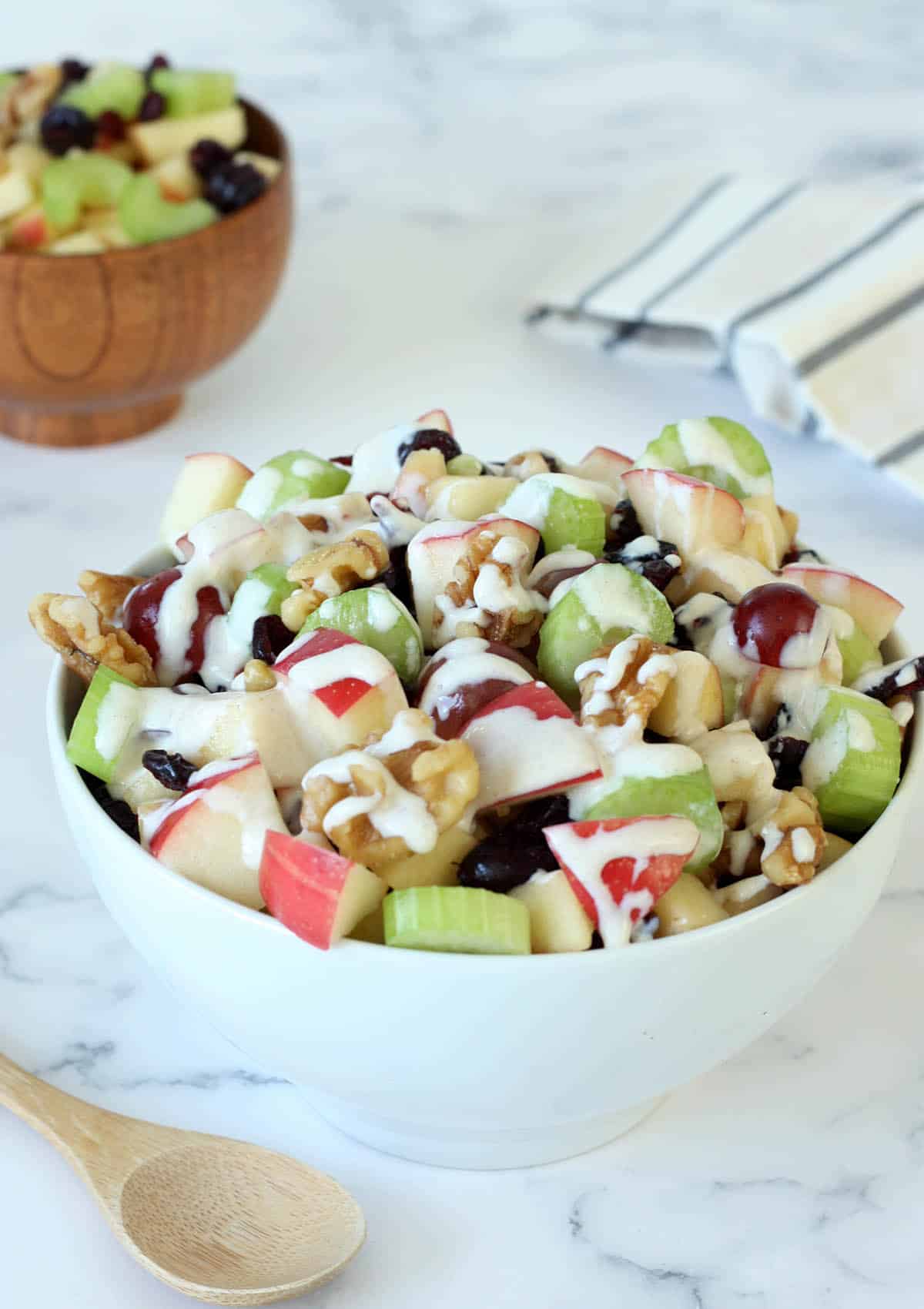 waldorf salad with apples, celery and grapes drizzled with dressing in a white serving bowl