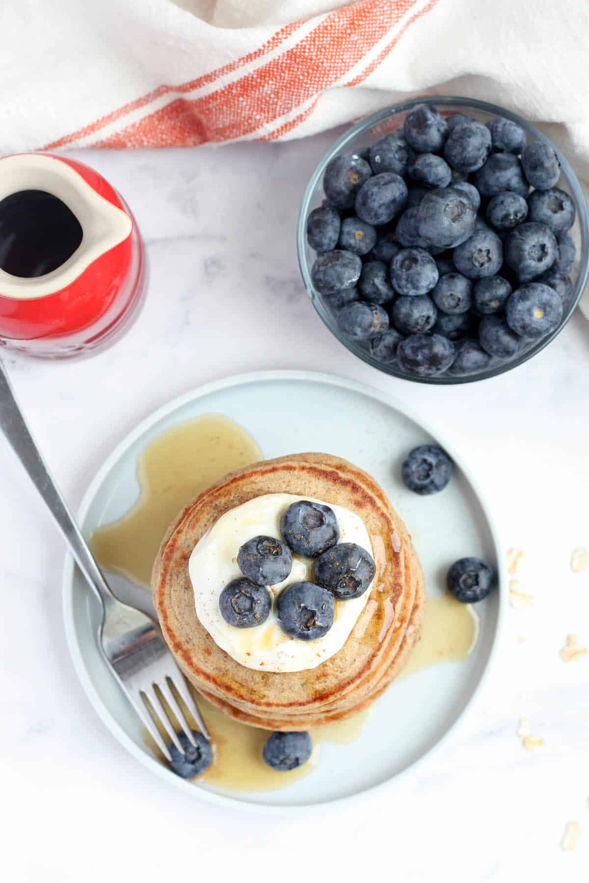 a plate of healthy pancakes next to a bowl of fresh blueberries