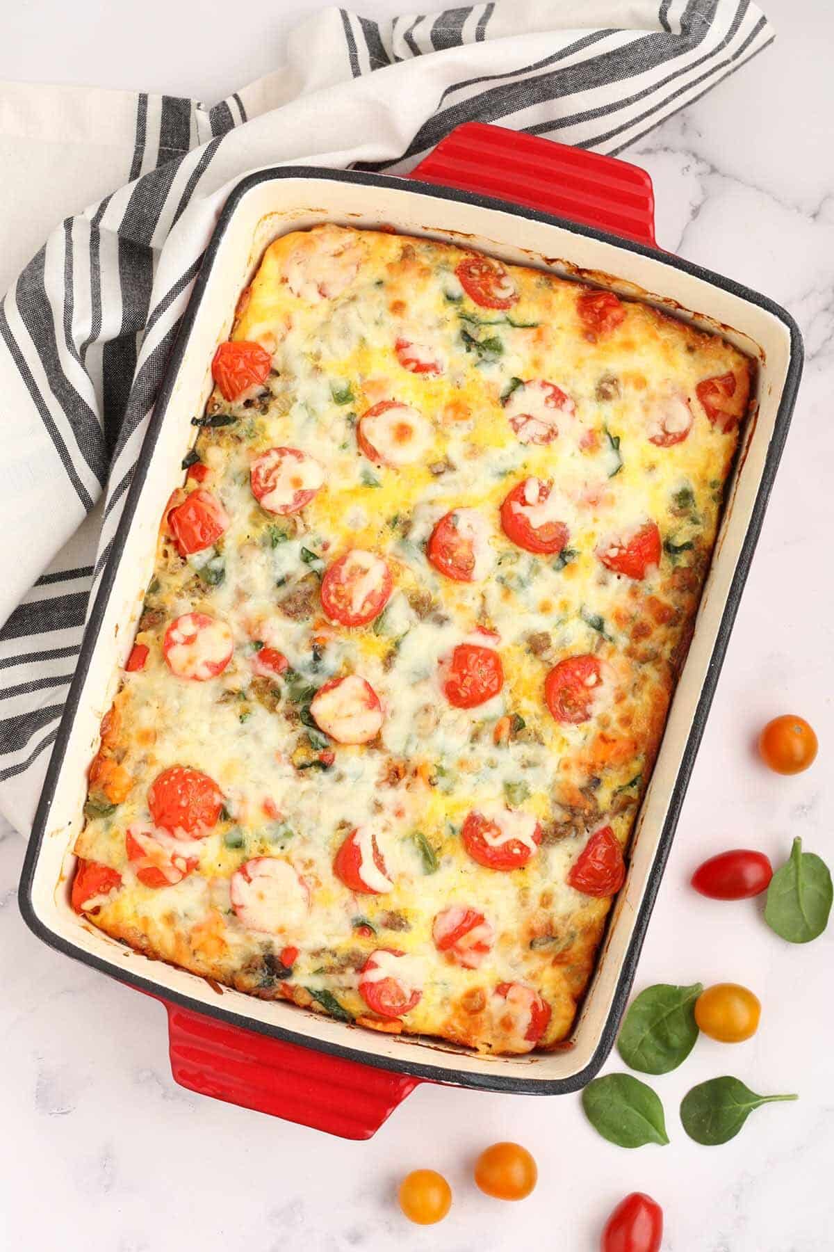 a red baking dish with sweet potato breakfast casserole with a striped linen