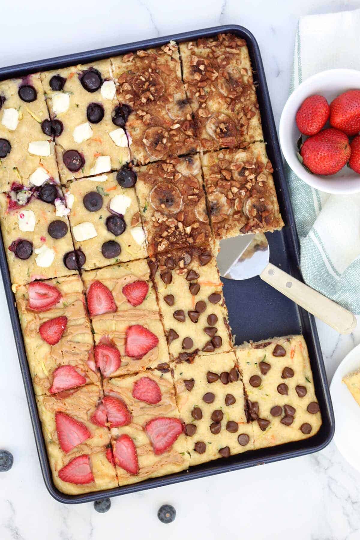 a close up of sheet pan pancakes with a bowl of strawberries