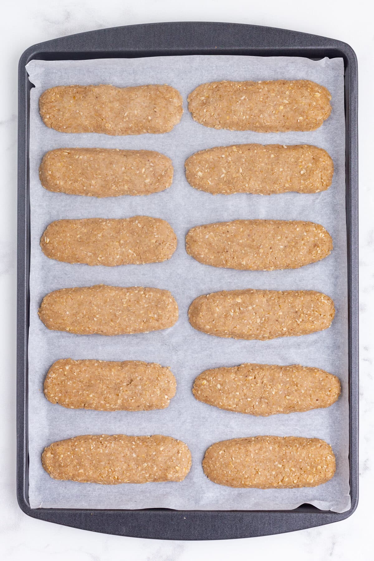 a dozen homemade teething biscuits on a parchment paper linked baking sheet