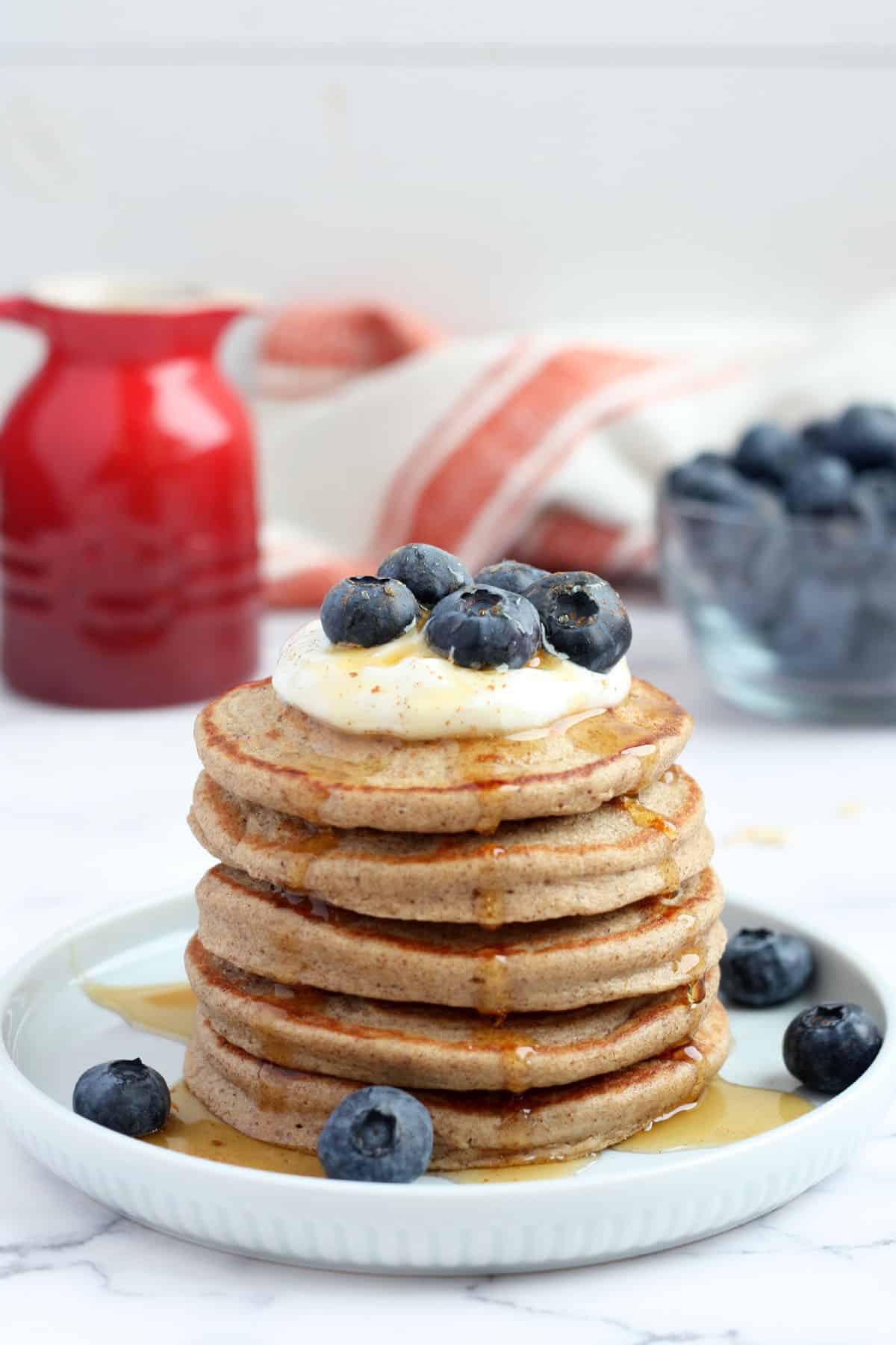 a stack of healthy pancakes topped with yogurt and fresh blueberries
