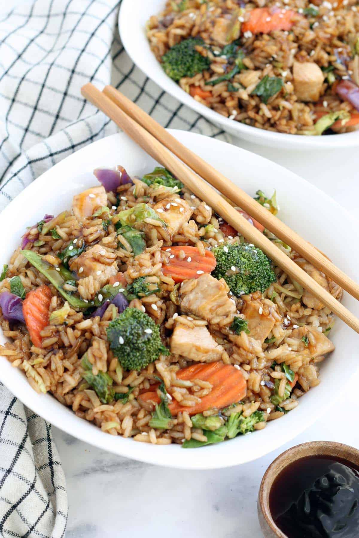 teriyaki chicken and rice in a white bowl with wooden chopsticks