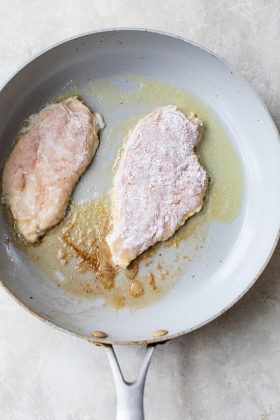chicken breast dredged in flour cooked in a skillet
