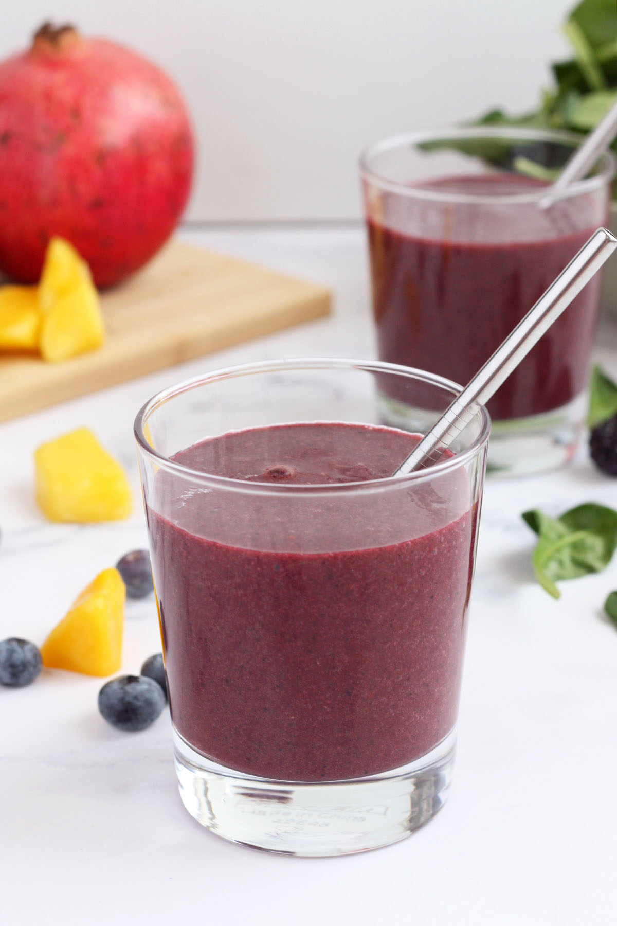 two immune boosting smoothies in a clear glass with fresh fruit in the background