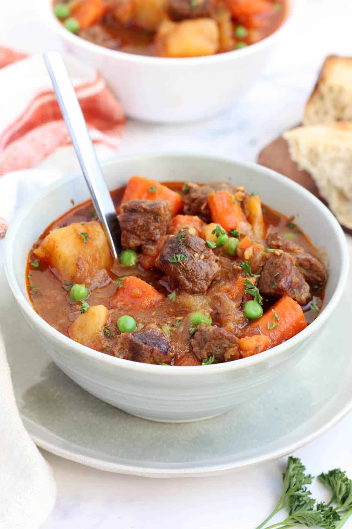 instant pot beef stew with beef chunks, carrots, potatoes, and green peas in a thick broth