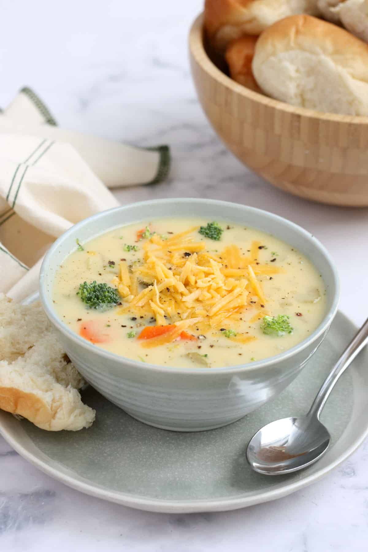 a bowl of crockpot cheesy vegetable soup with fresh bread