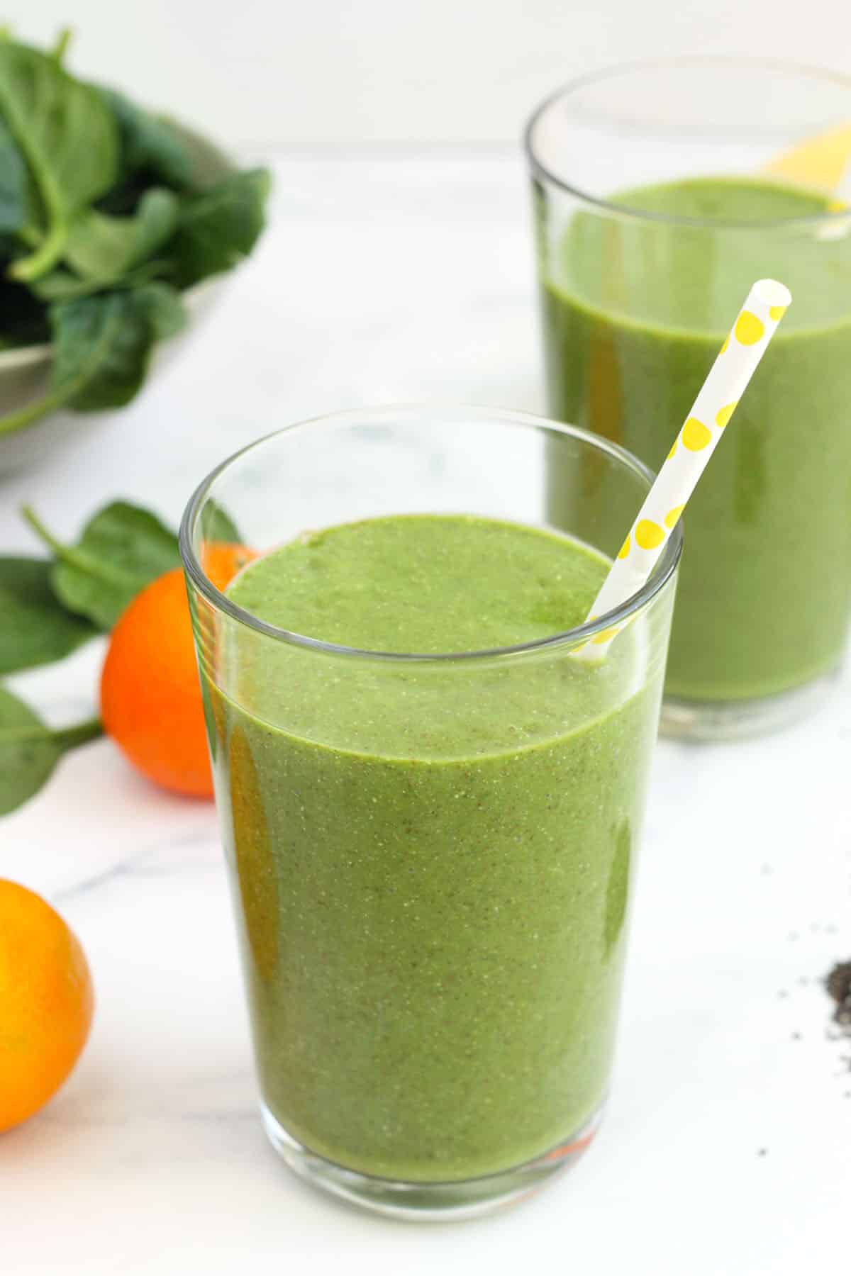green smoothie in a clear glass with a yellow polka dot straw