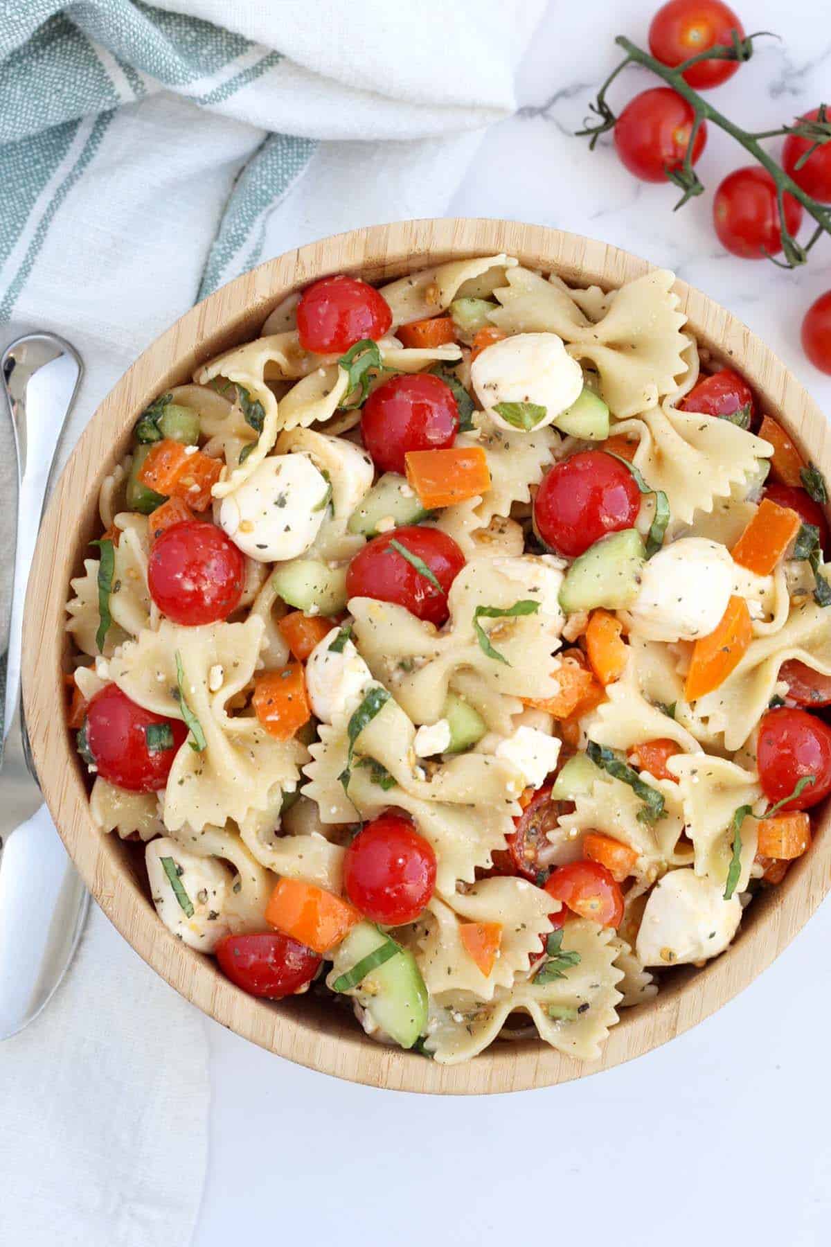 easy pasta salad in a large wooden serving bowl with fresh cherry tomatoes