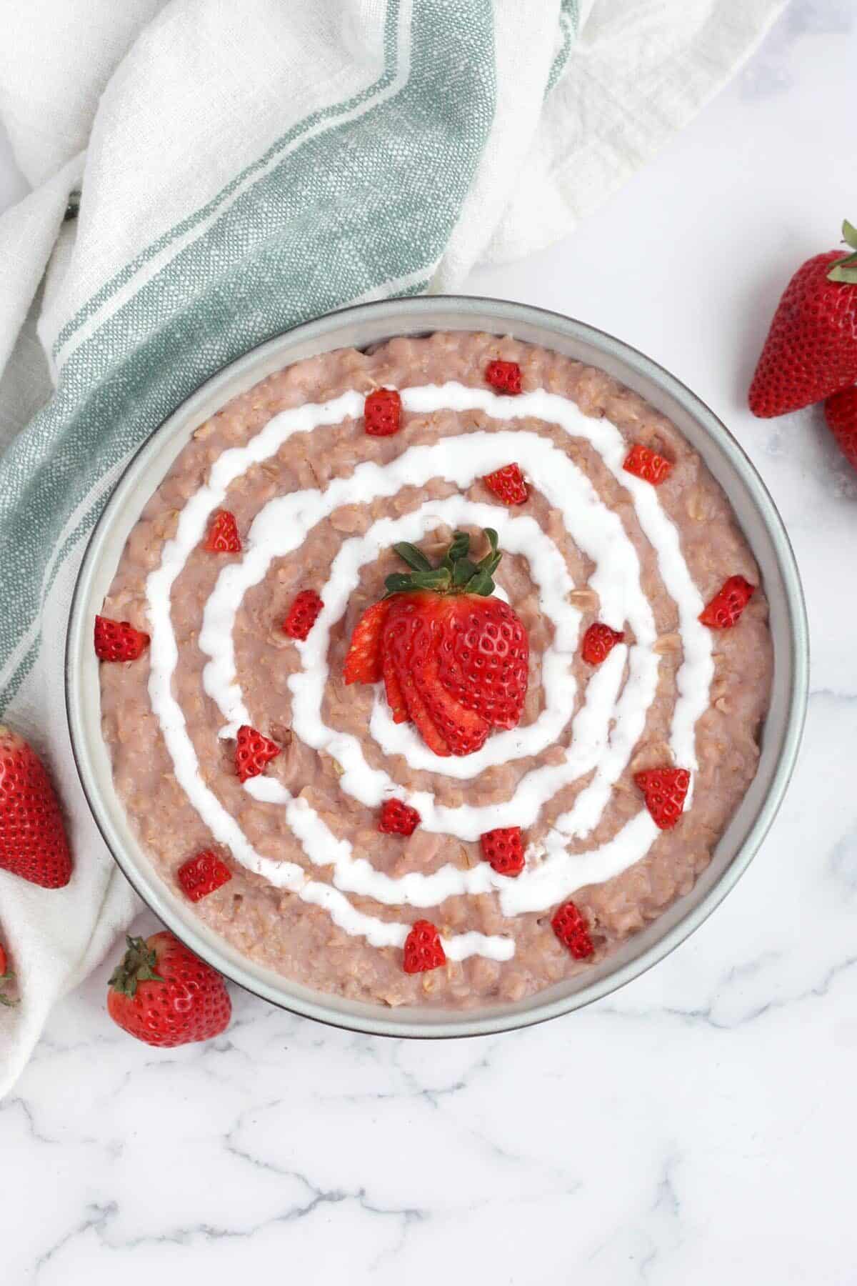 strawberries and cream oatmeal in a serving bowl topped with diced strawberries