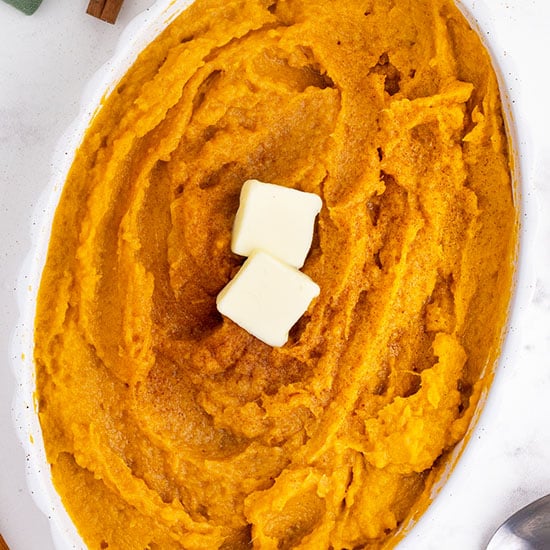 mashed sweet potatoes in a white dish with butter on top
