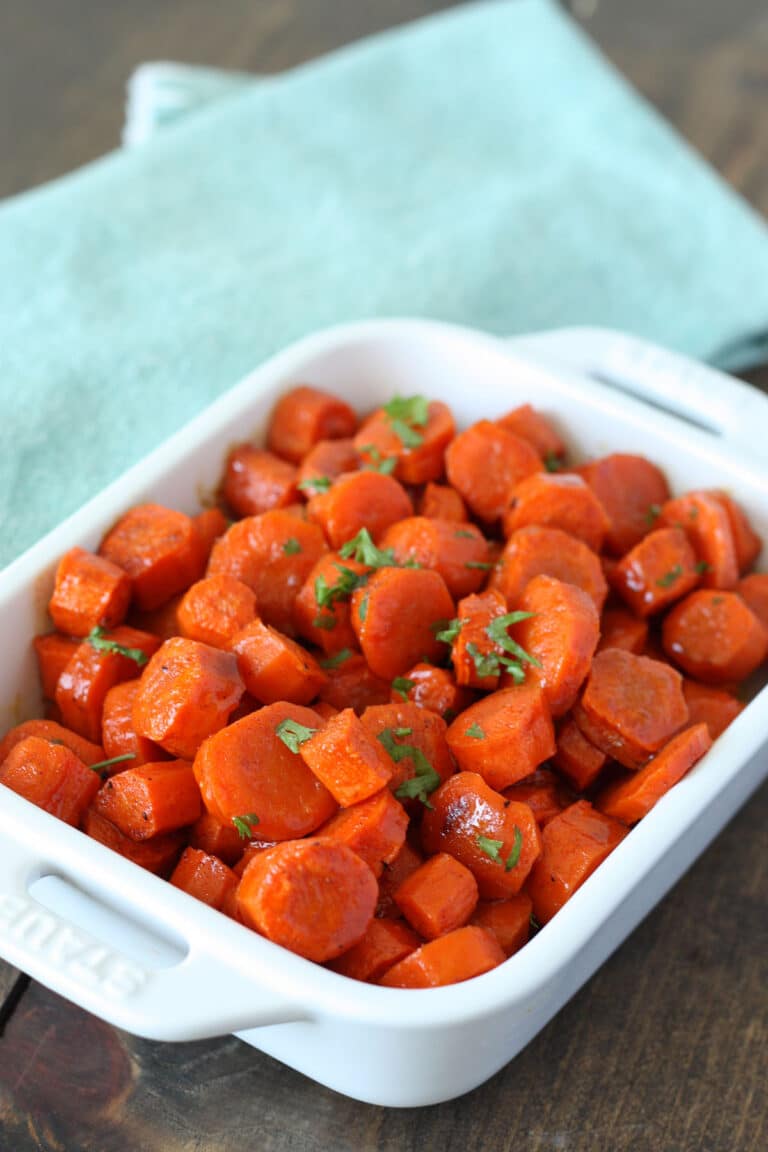 roasted honey glazed carrots in a white baking dish with a blue linen in the background