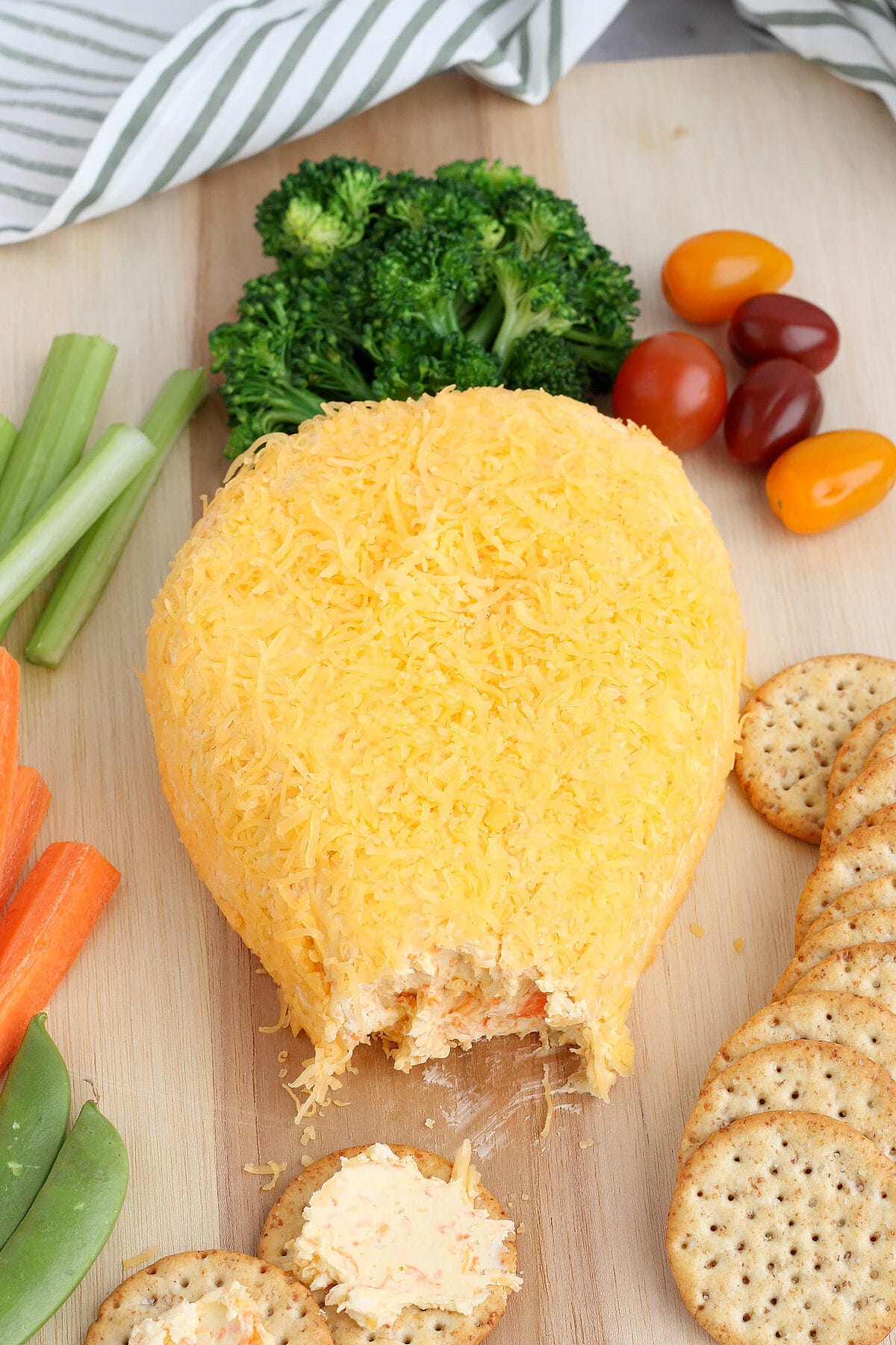 a cheeseball shaped like a carrot with crackers and vegetables