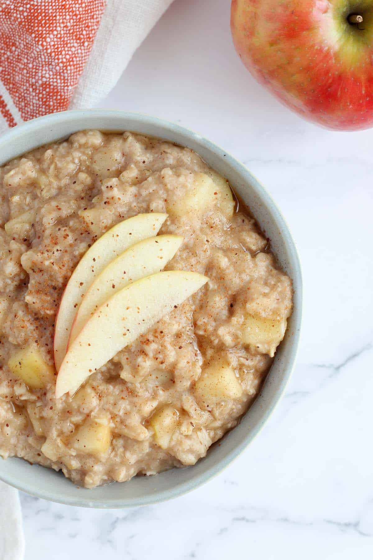 a bowl of apple cinnamon oatmeal topped with fresh apple slices