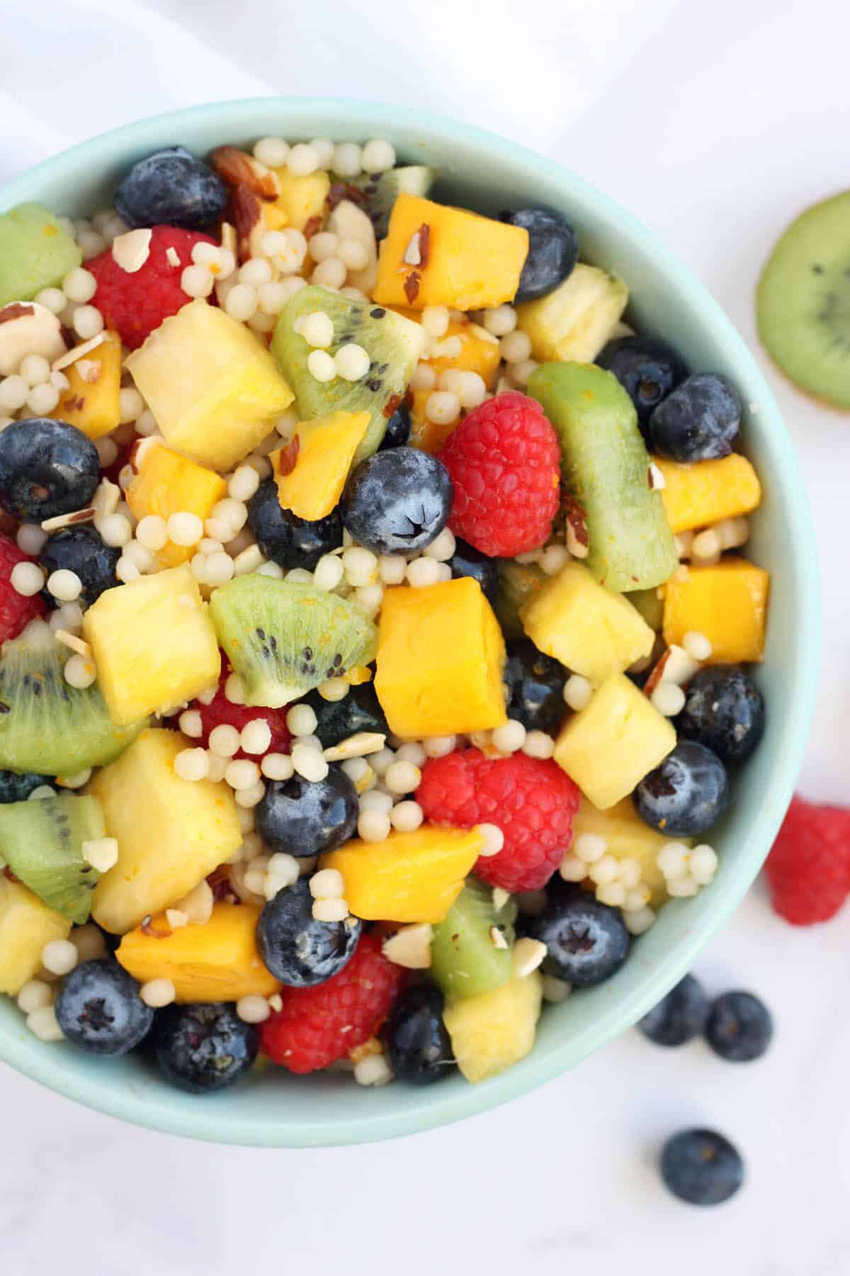 a bowl of fruit salad with couscous and almond slices