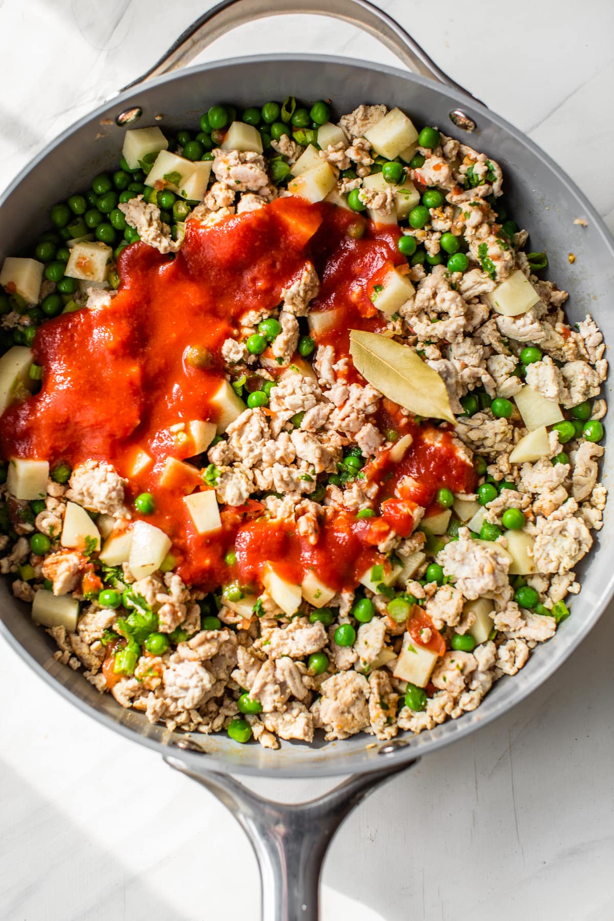 skillet with ground turkey, peas, tomatoes and potatoes