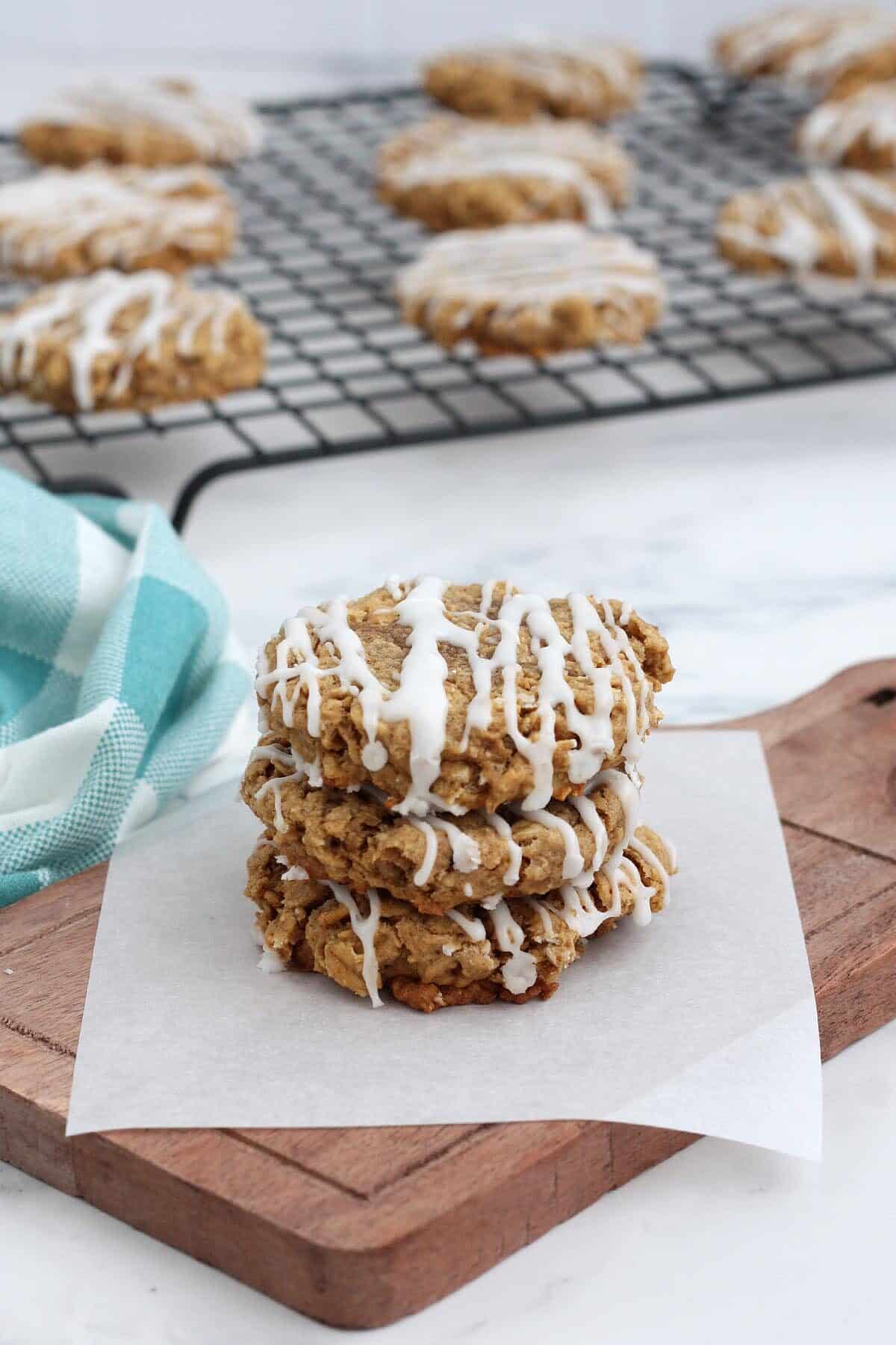 a stack of iced oatmeal cookies on a wooden board