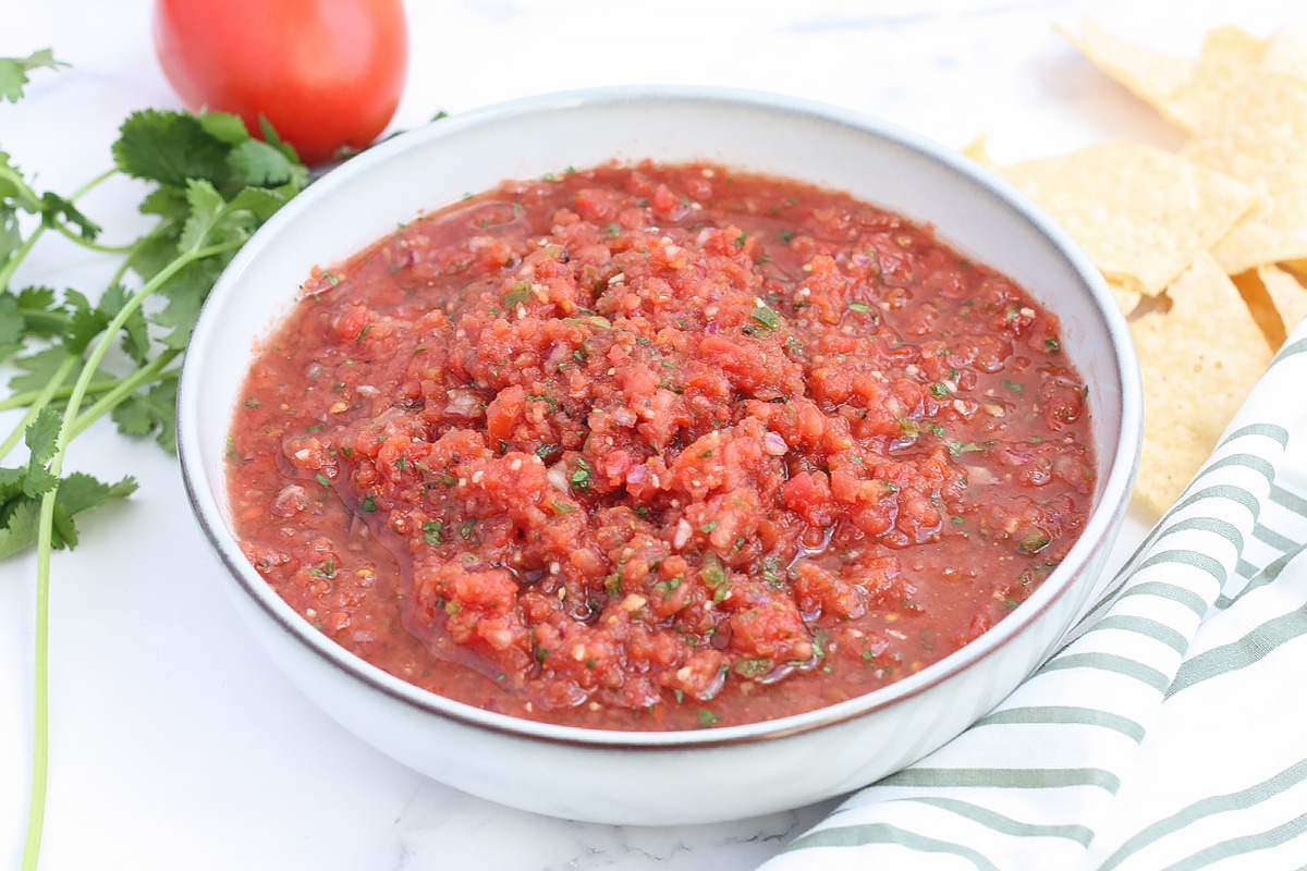 a serving bowl of homemade salsa with tomatoes and cilantro