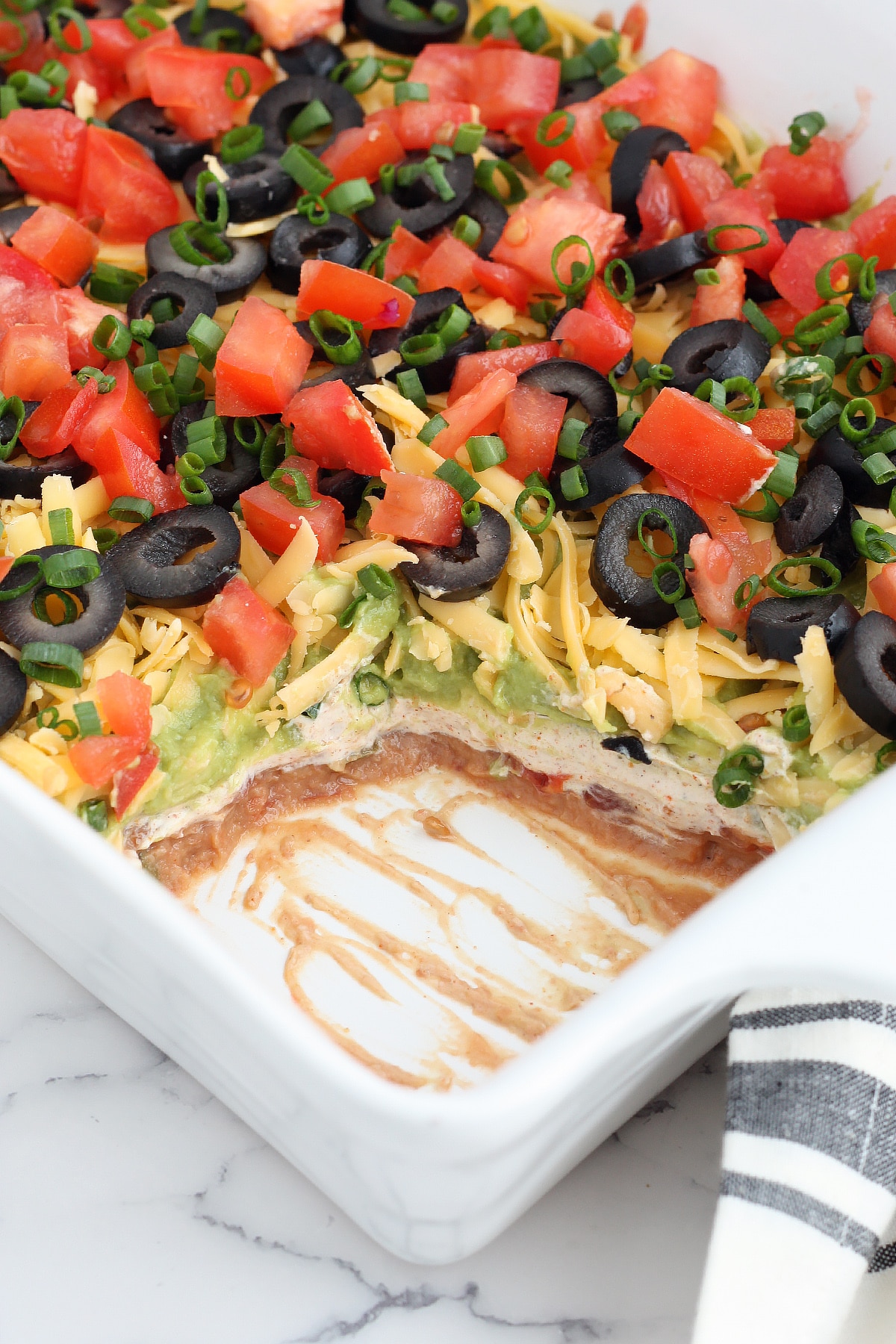close up image of 7 layer dip with a scoop removed