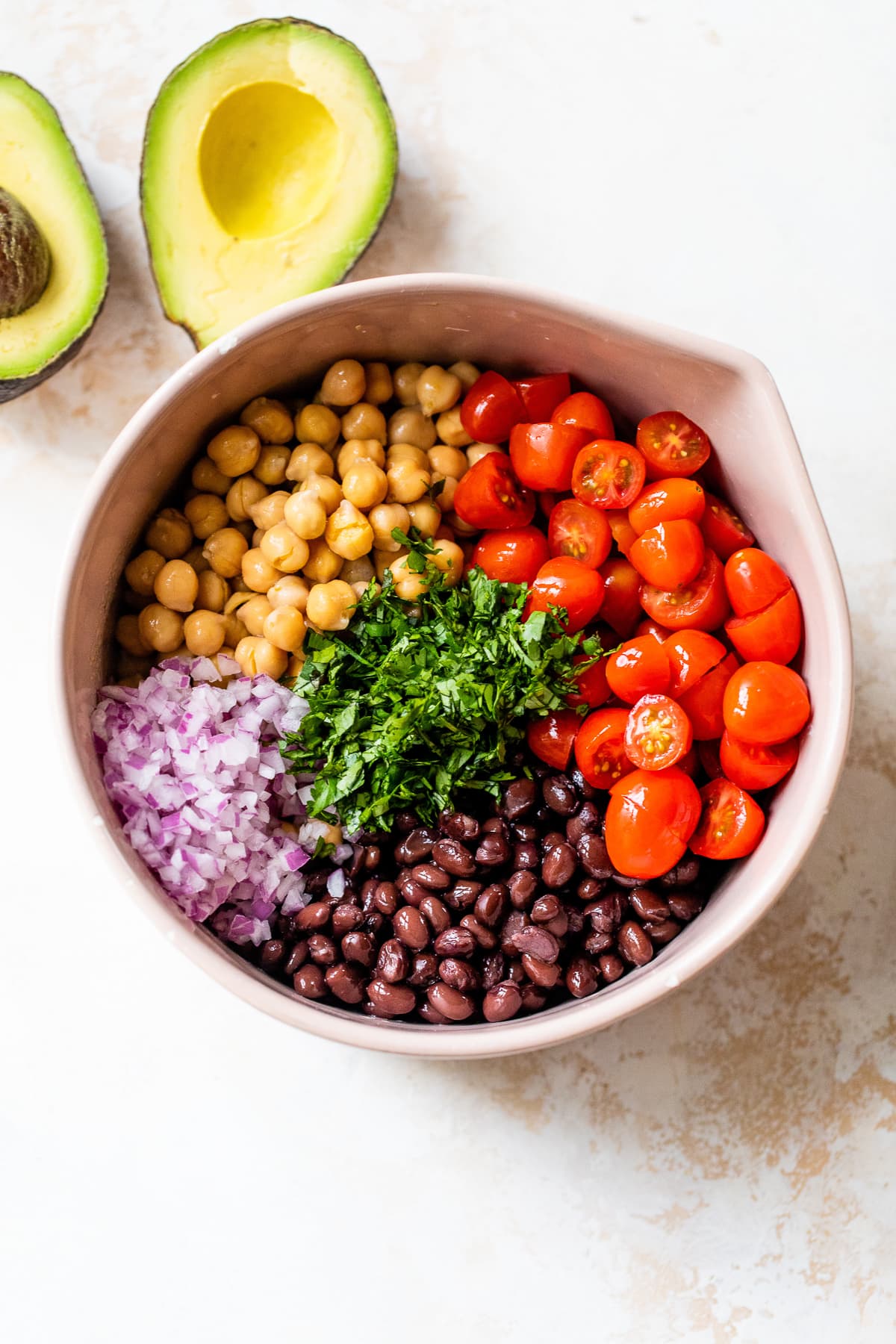 black beans, chickpeas, avocado and tomatoes with lime in a bowl.