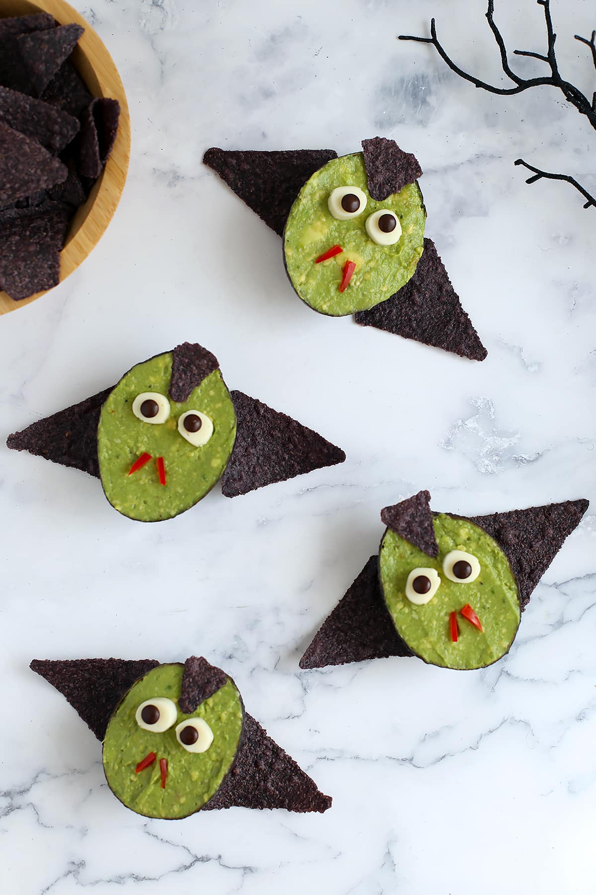 Cute little vampires made out of avocado halves with corn chip bat wings.