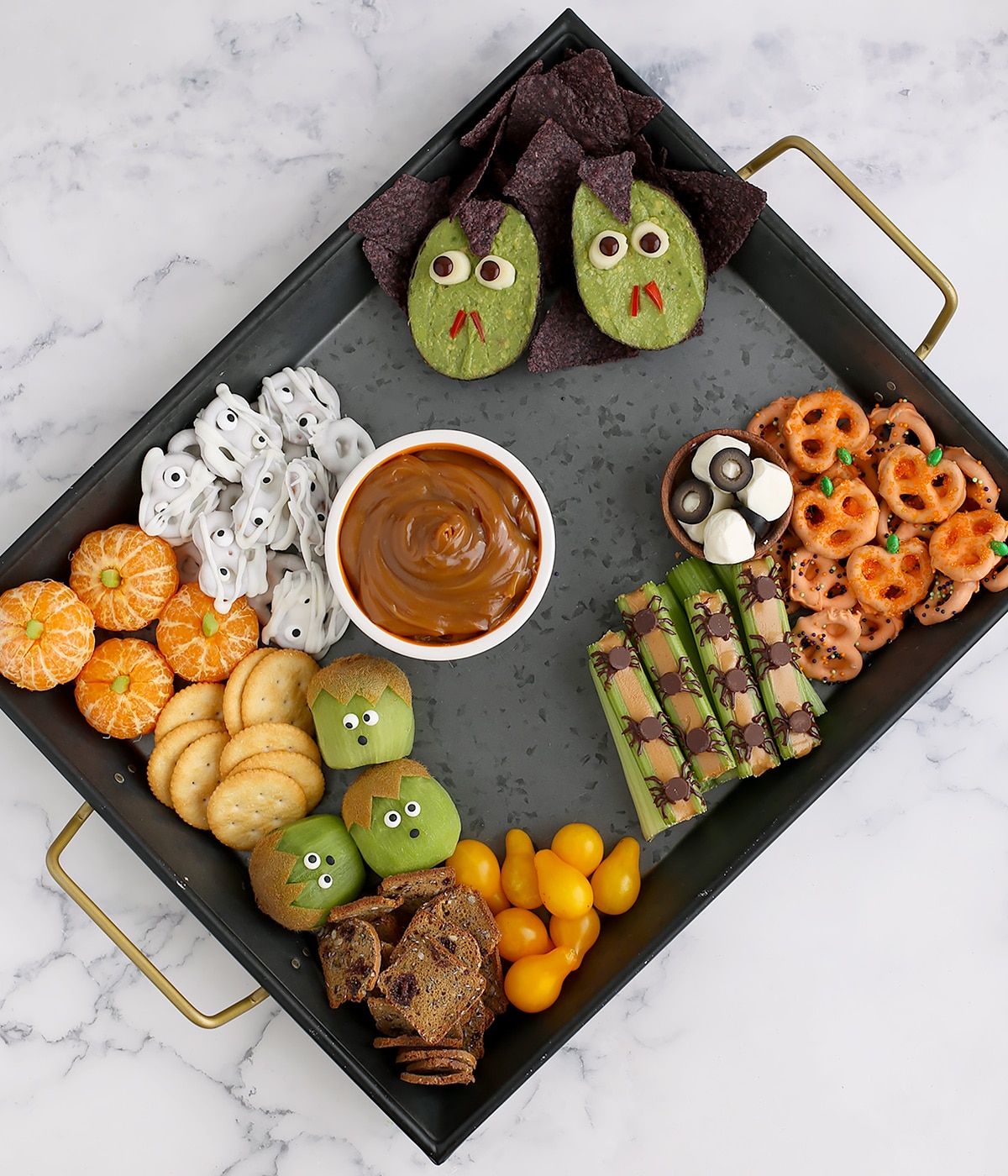 A black tray halfway filled with halloween snacks.