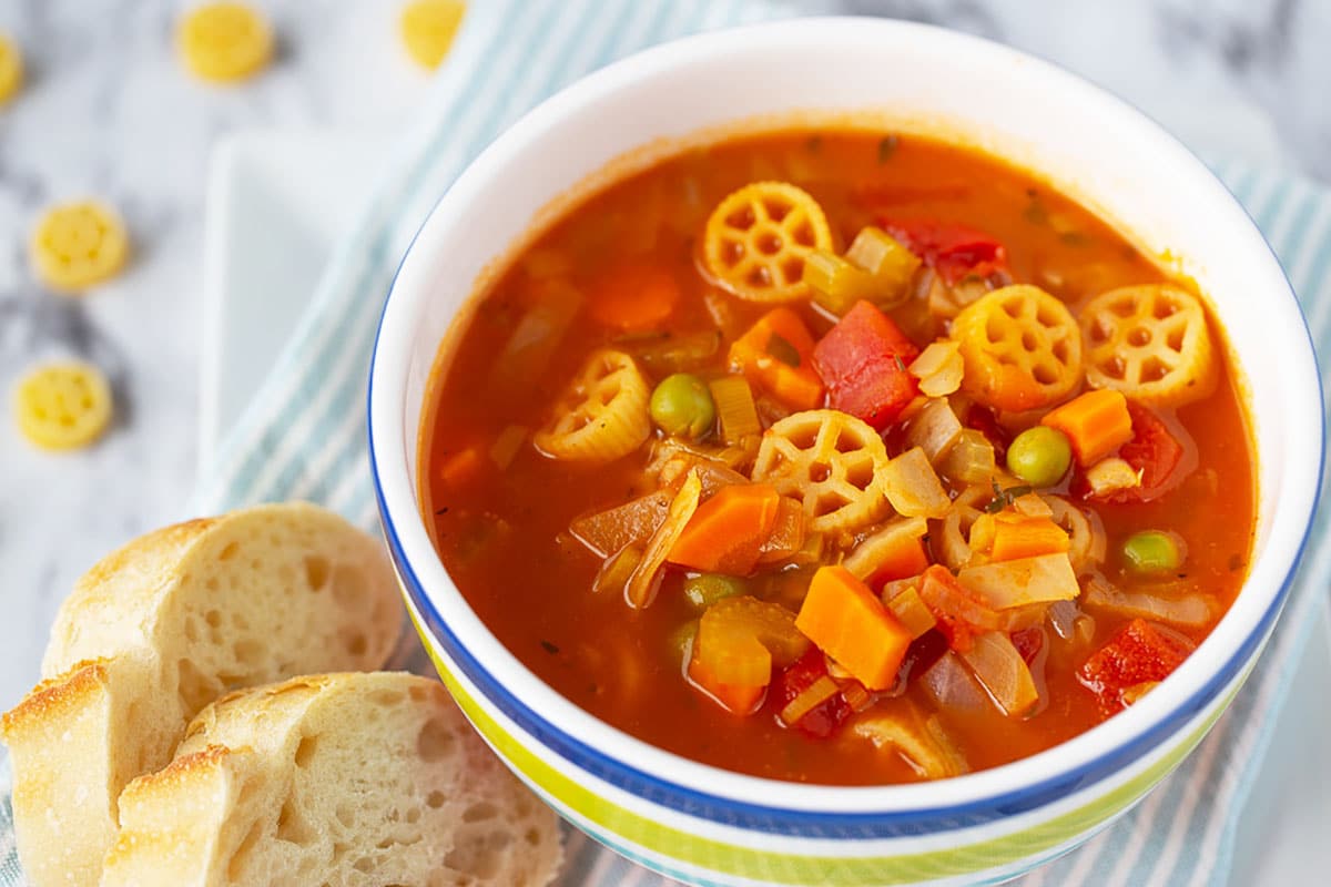 minestrone soup in a colorful bowl with crusty bread on the side