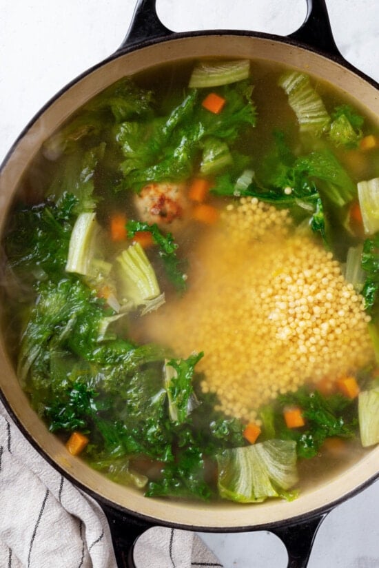 Greens added to a pot of broth and veggies