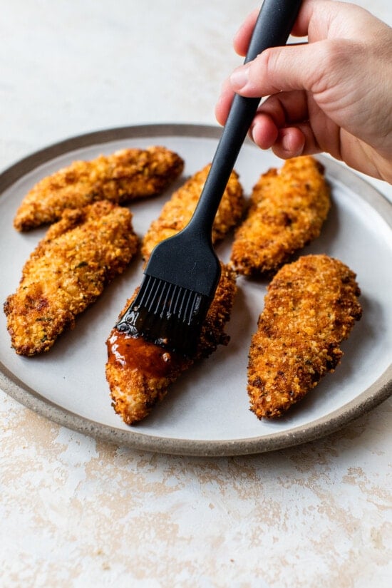 brushing bbq sauce on chicken fingers